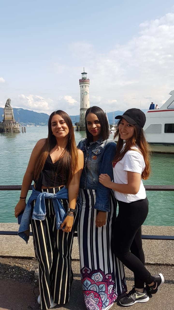 Drei Au-pairs gemeinsam am Lindauer Hafen mit Löwe, Leuchtturm und Bodensee